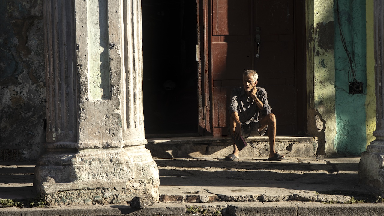 A Cuban sitting at the entrance of a building in Havana.