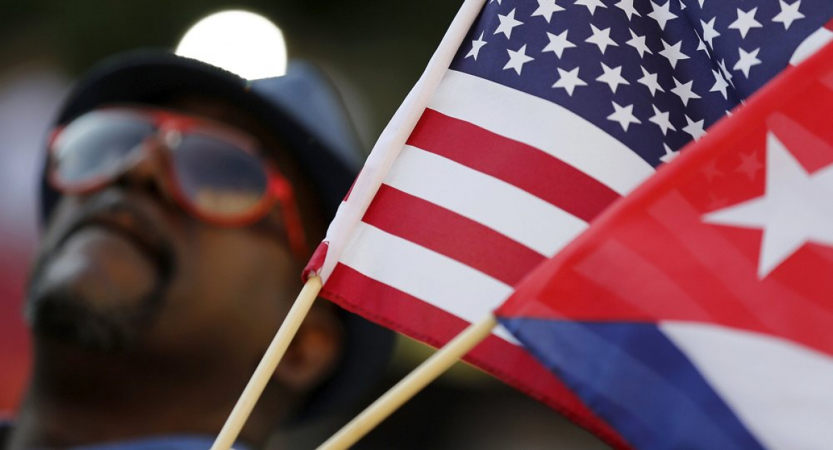 Un hombre sostiene banderas de EEUU y Cuba. 