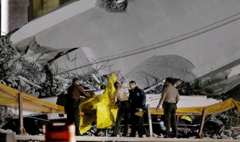 Policías de Miami-Dade cubren uno de los vehículos aplastados tras el colapso del puente de FIU. 
