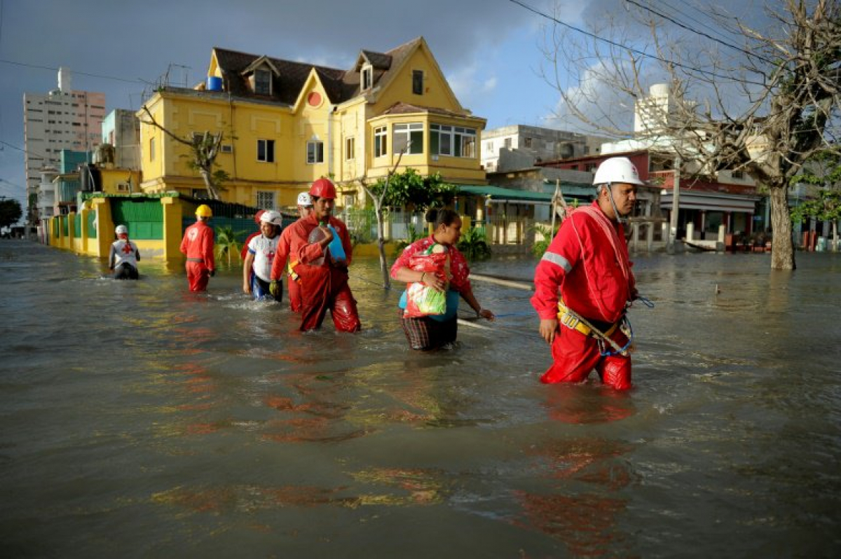 Personal de rescate ayuda a varias personas a cruzar calles inundadas en La Habana.