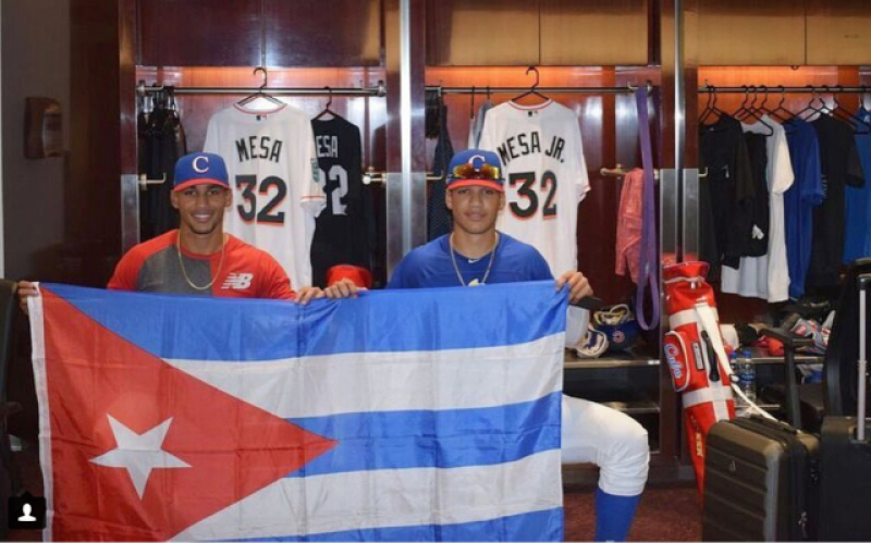 Víctor Víctor Mesa y Víctor Mesa Jr., con una bandera cubana en el clubhouse de los Marlins.