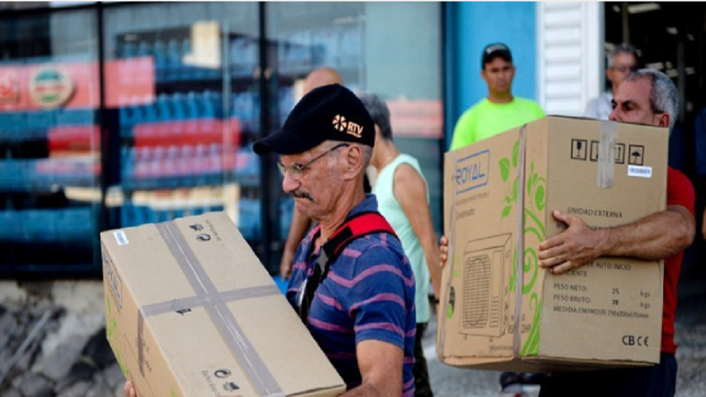 Dos cubanos cargan electrodomésticos recién adquiridos.