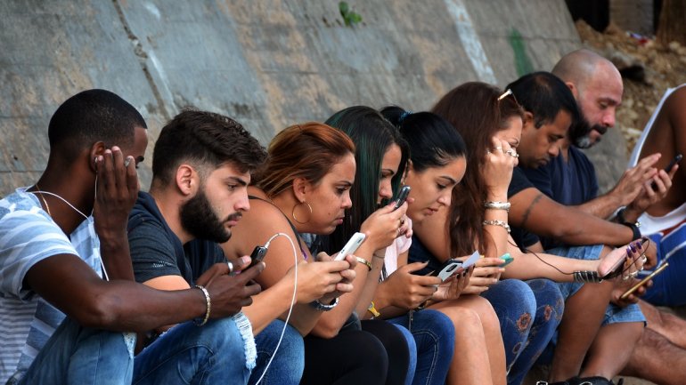 Cubanos revisando internet en un punto WiFi.