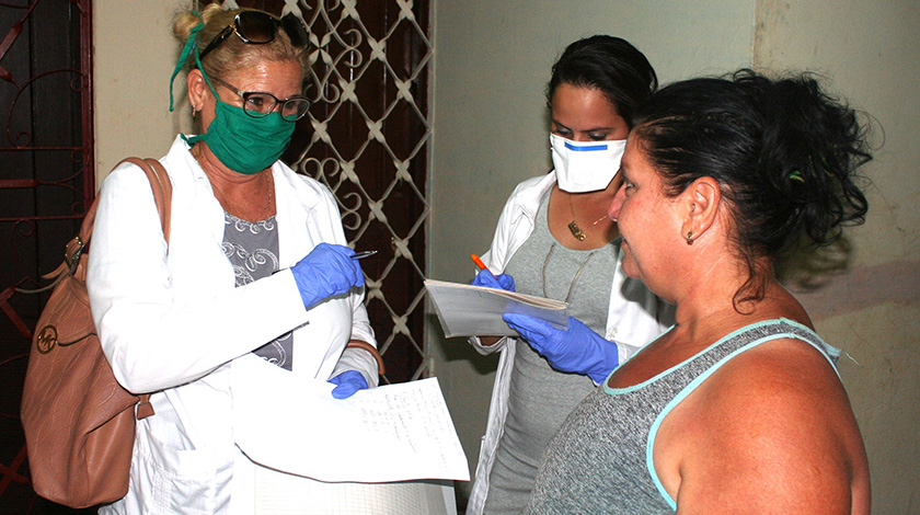 Dos profesionales de la salud en una pesquisa en Cuba.