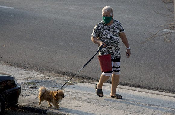 Un hombre con nasobuco saca a su perro en La Habana