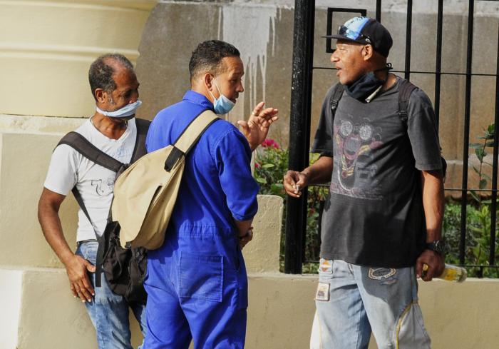 Tres hombres conversan en una parada en La Habana.