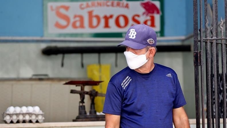 Un hombre con nasobuco sale de una carnicería en Cuba.