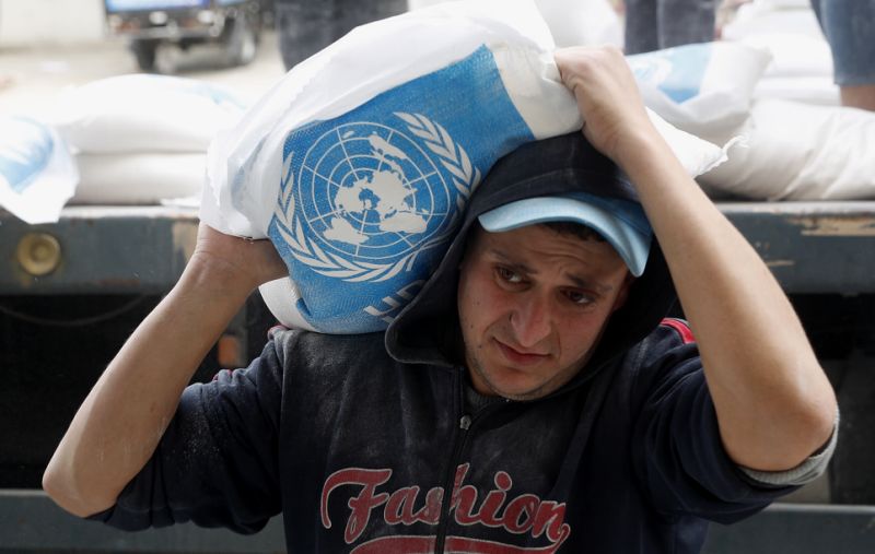 Un trabajador palestino carga sacos de harina distribuidos por una Agencia de Naciones Unidas a familias pobres de desplazados en Sheikh Redwan, Gaza.