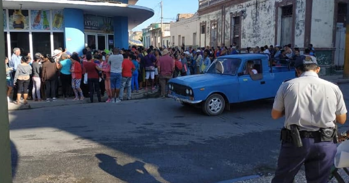 Cola en Cuba vigilada por un policía.