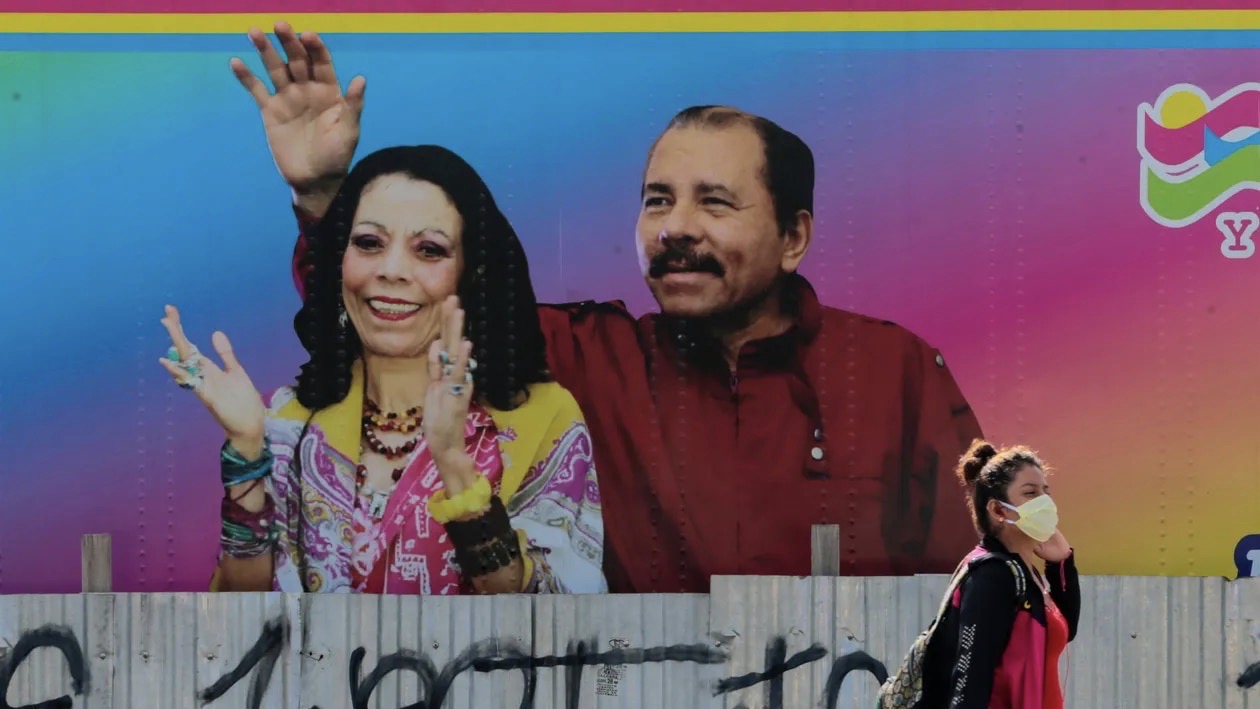 Una mujer con mascarilla pasa ante un cartel de Rosario Murillo y Daniel Ortega en Nicaragua.
