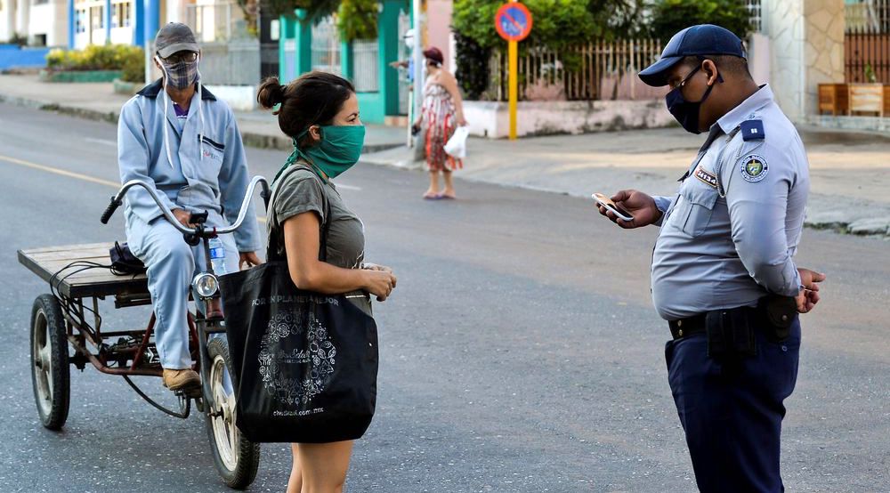 Un policía revisa la identificación de una mujer en La Habana, durante la cuarentena.