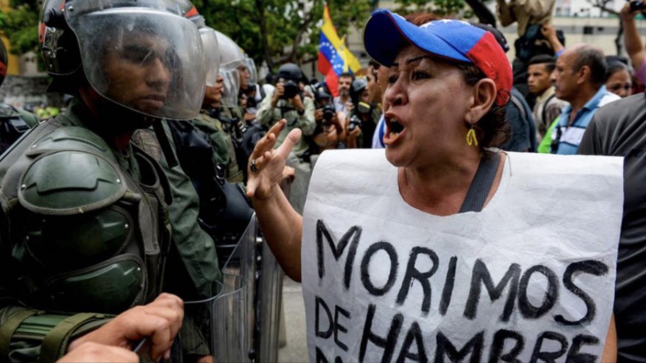 'Morimos de hambre', reza el cartel de una venezolana enfrentada a la policía.