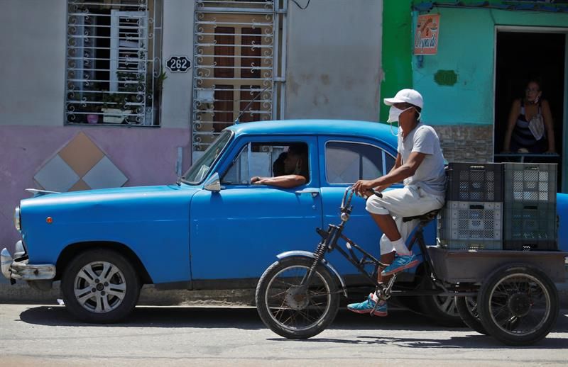 Dos vehículos transitan por una calle en Cuba.