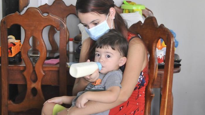 Una madre cubana alimenta a su hijo con un biberón de leche.