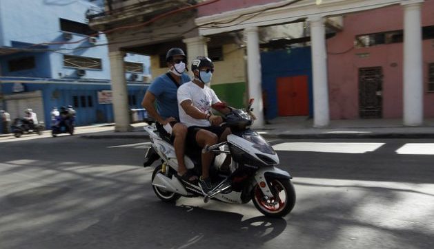 Dos cubanos en una moto eléctrica.