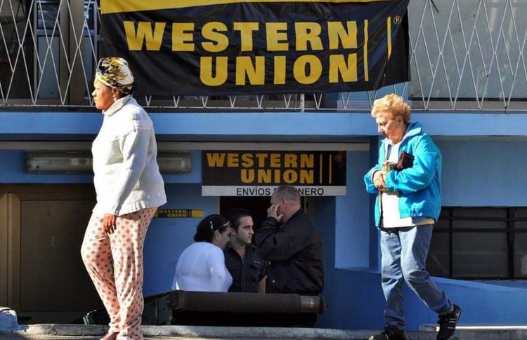 Dos mujeres caminan frente a una oficina de Western Union en Cuba.