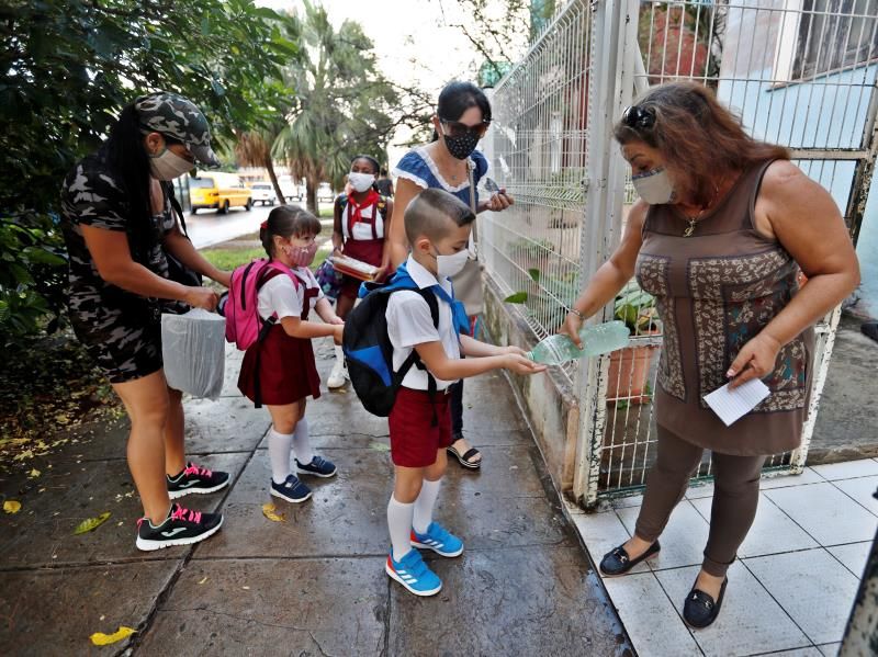 Escolares cubanos se desinfectan las manos antes de entrar a clases.