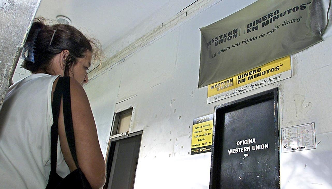 Una cubana epera ante la puerta de una oficina de Western Union.