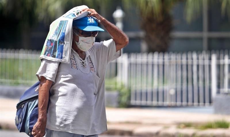 Un cubano se cubre del sol con un periódico.