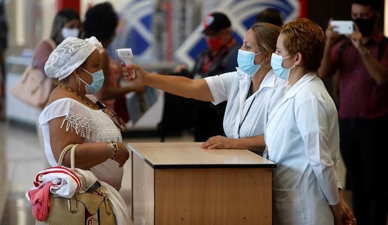 Sanitarios cubanos toman la temperatura a una mujer.