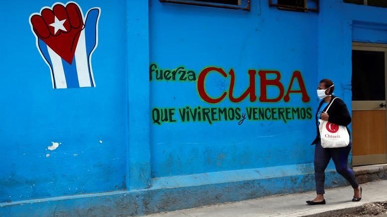 Una mujer cubana pasa por delante de una pared con publicidad política.