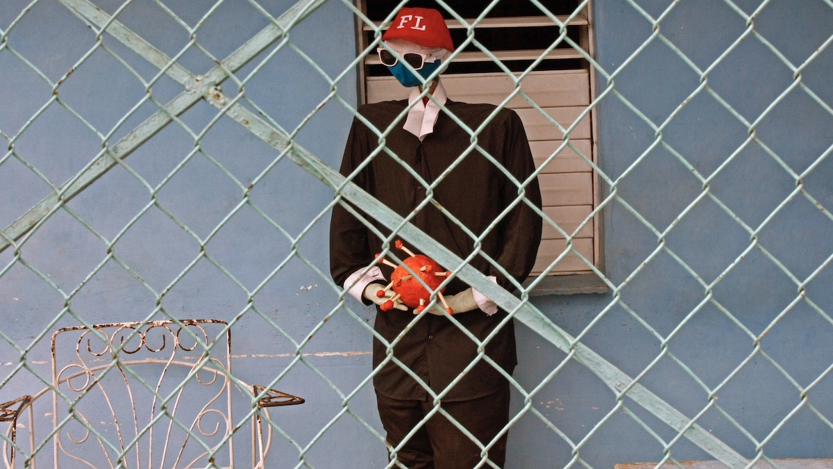 Muñeco con un modelo de virus en las manos, en una casa de La Habana.