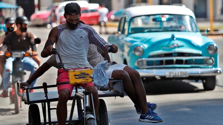 Cubanos en un triciclo en La Habana.