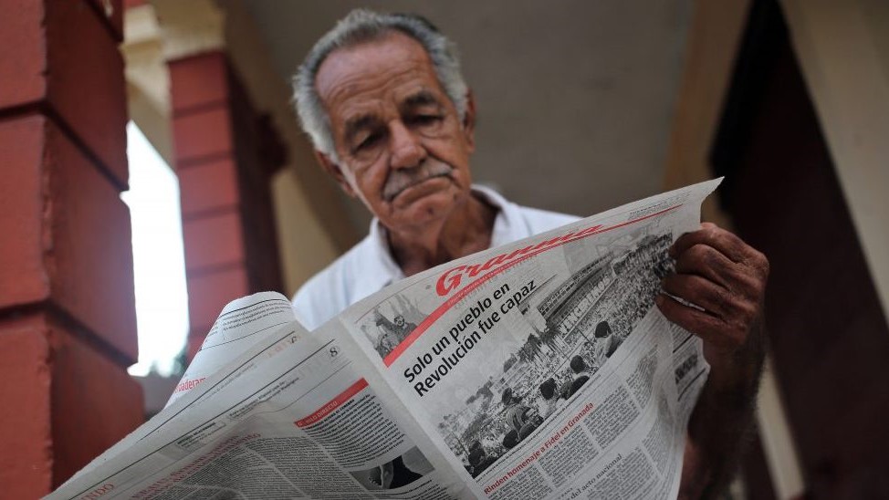 Un hombre lee un periódico 'Granma'.