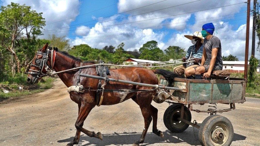 Dos cubanos con nasobuco en un coche de caballos en Cuba.