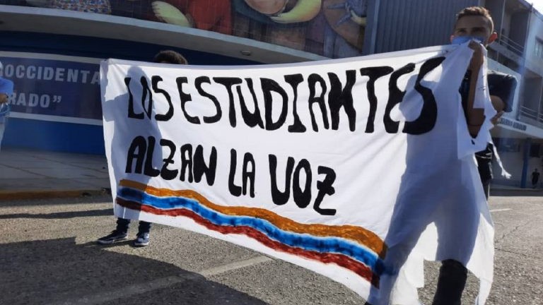 Estudiantes universitarios venezolanos sostienen un cartel.
