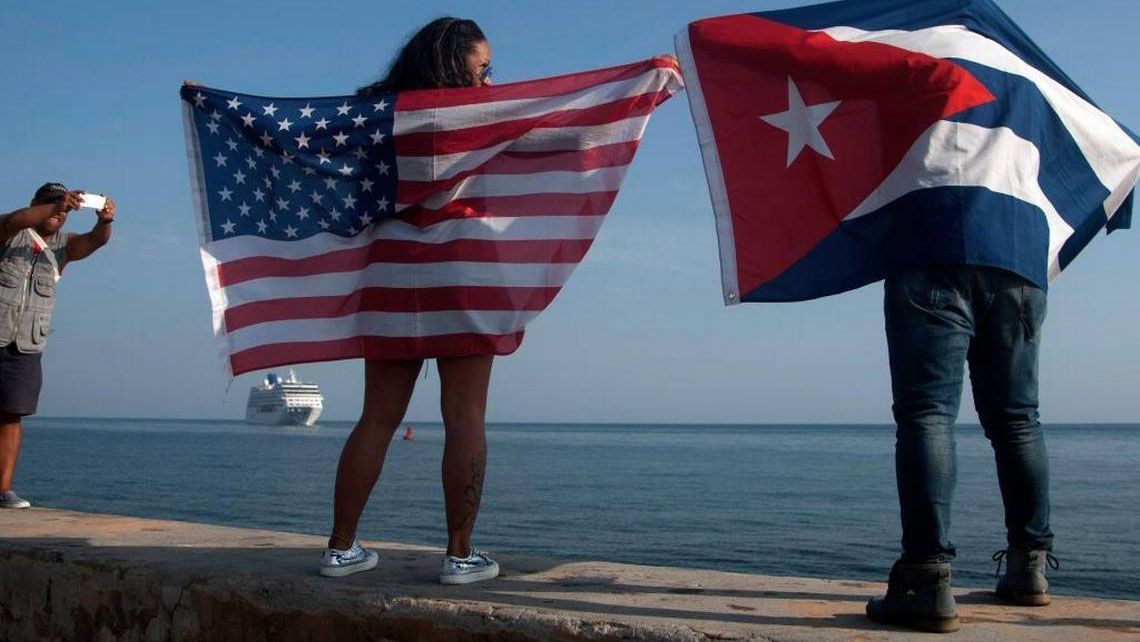 Cubanos con banderas de EEUU y Cuba en el Malecón habanero.