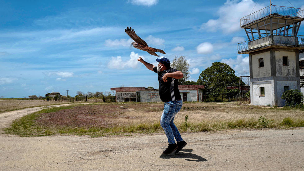 Uno de los ingenieros cubanos sostiene un dron con forma de ave.