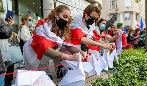Bielorrusos atan aviones de papel a un cordón durante una manifestación en Polonia frente a la oficina de la Comisión Europea en Varsovia. 