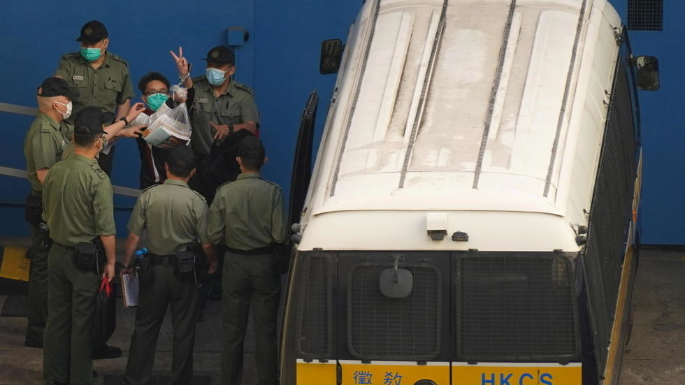 El activista Figo Chan hace gestos mientras camina hacia una camioneta de la prisión para dirigirse a la Corte.