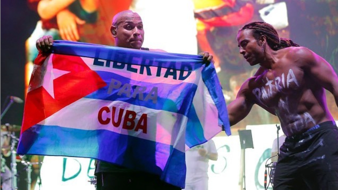 Alexander Delgado y Yotuel Romero con una bandera de Cuba en un concierto.