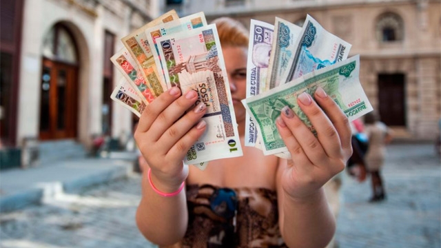 Una mujer muestra pesos cubanos y pesos convertibles.