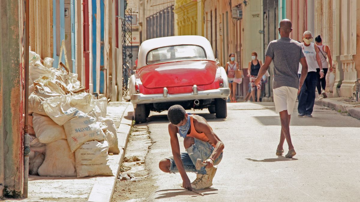 Un joven cubano con mascarilla hace labores de albañilería.
