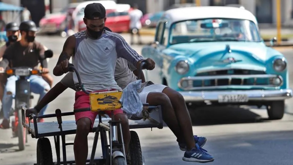 Cubanos en un triciclo en La Habana.