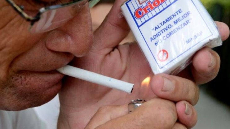 Un cubano enciende un cigarrillo.