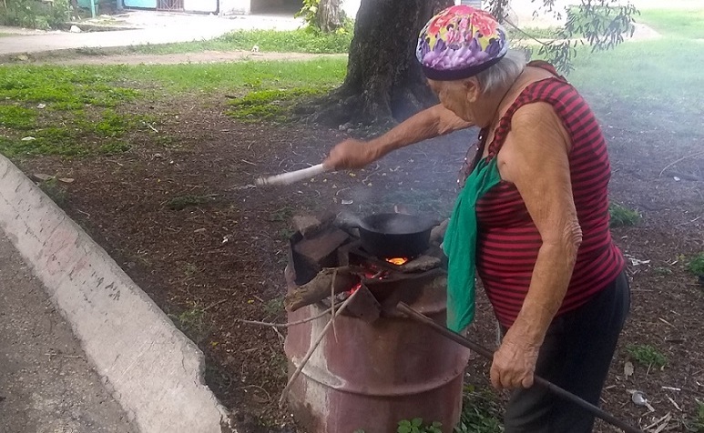 Una anciana preparando alimentos antes del paso de Elsa en una cocina improvisada en Santiago de Cuba.