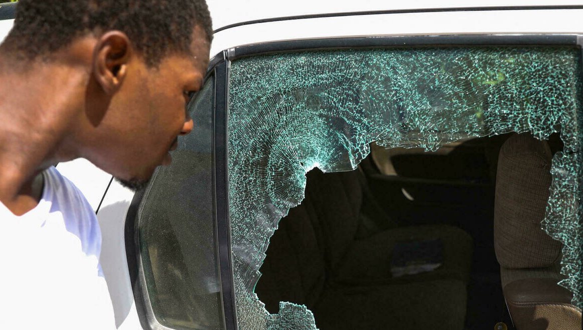 Un hombre mira los impactos de bala en un carro fuera de la residencia presidencial en Puerto Príncipe.