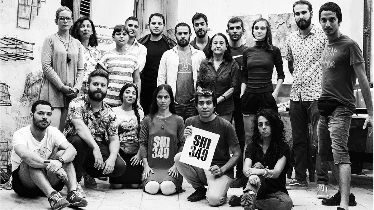 Hamlet Lavastida sostiene un cartel contra el Decreto 349 junto a un grupo de artistas cubanos.