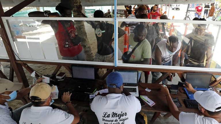 Migrantes compran tickets para viajar a Capurganá, Panamá, en el embarcadero de Necoclí, Colombia.