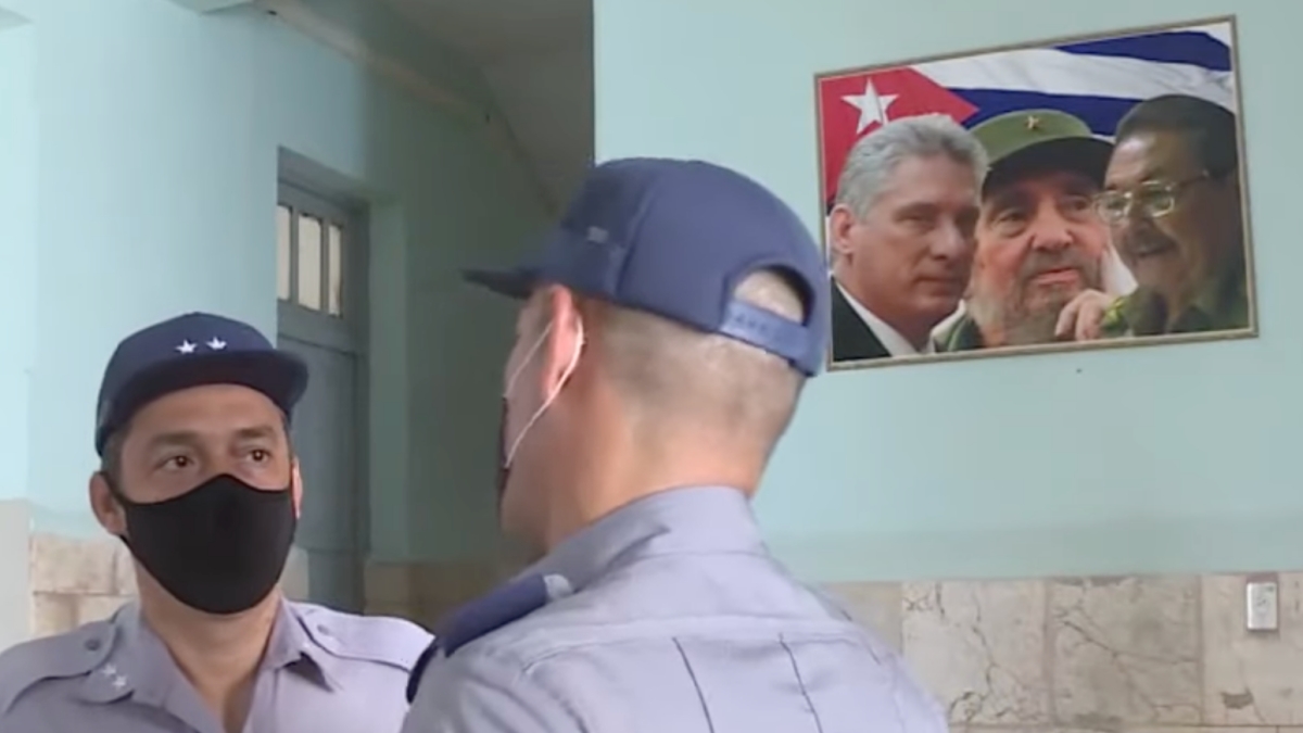 Los policías cubanos Omar Herrera y Youbel Laffita con un cuadro de Díaz-Canel, Fidel y Raúl Castro.