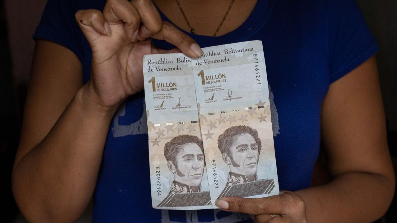 Una mujer muestra billetes de bolívares.