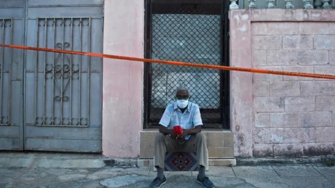 Un hombre sentado en la entrada de una vivienda en La Habana.