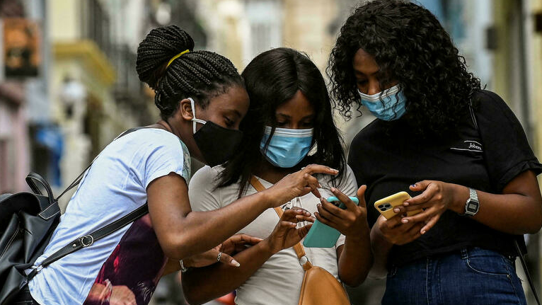 Tres jóvenes cubanas navegan en internet con sus teléfonos.