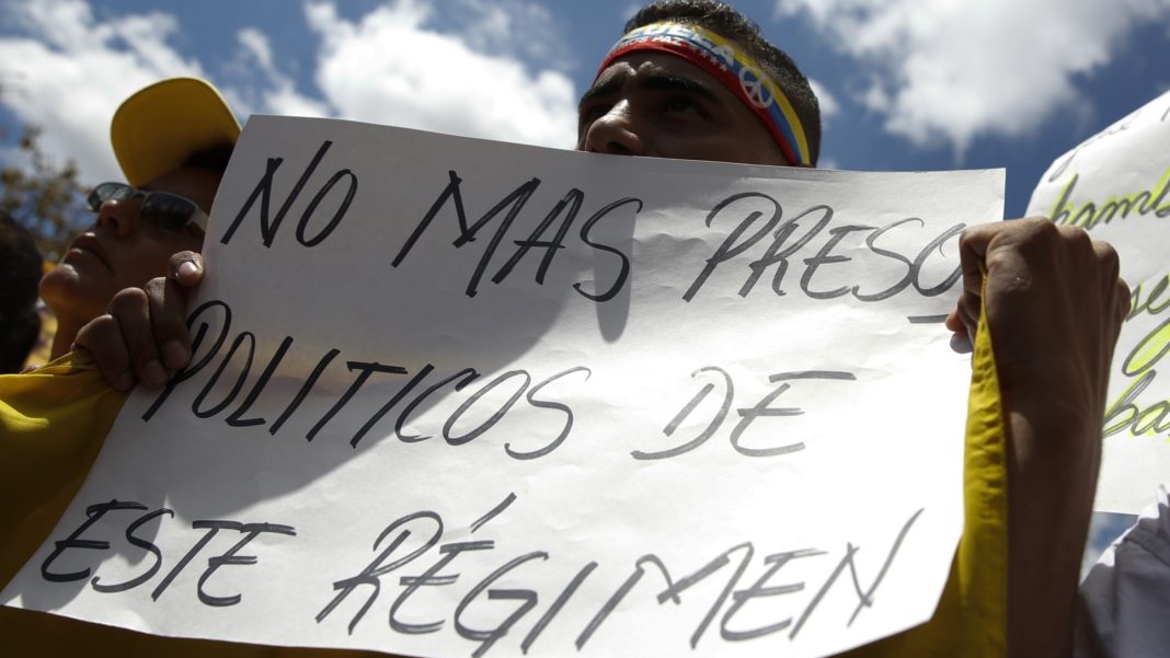 Un venezolano con un cartel contra los presos políticos de Maduro.