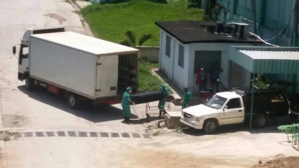 Personal de salud mete un ataúd en un camión en Bayamo.