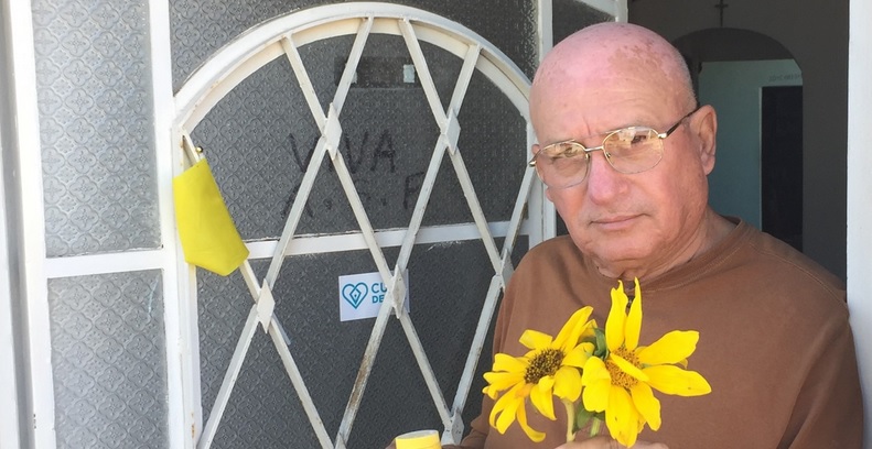 Félix Navarro en la puerta de su casa con girasoles para la Virgen de la Caridad del Cobre.
